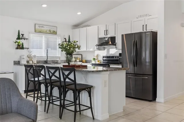 a kitchen with stainless steel appliances a refrigerator a stove a dining table and chairs