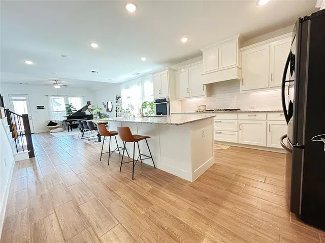 a kitchen with stainless steel appliances granite countertop a table chairs refrigerator sink and cabinets