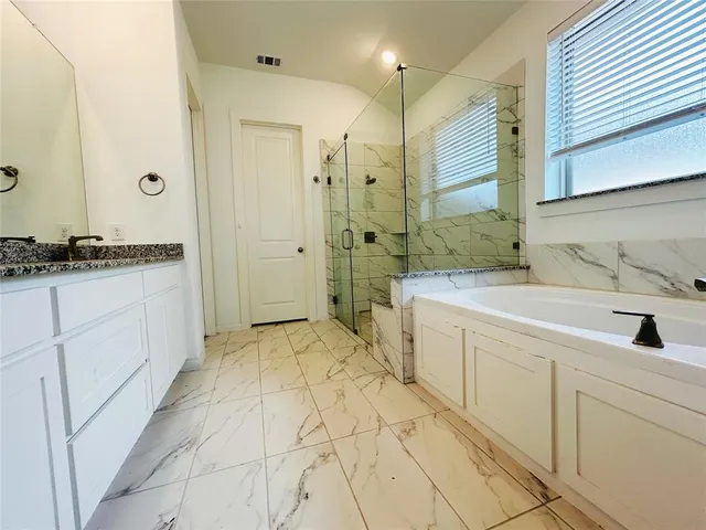 a spacious bathroom with a granite countertop sink mirror and a bathtub