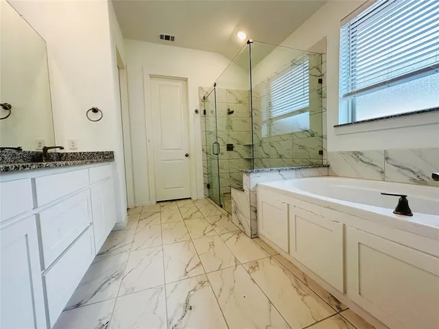 a spacious bathroom with a granite countertop sink mirror and a bathtub