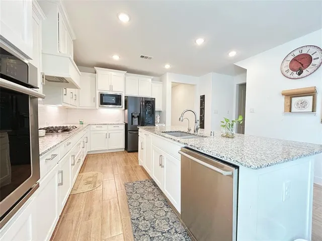 a large kitchen with stainless steel appliances granite countertop a stove a sink and a refrigerator