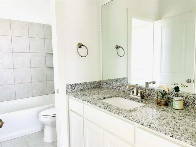 a bathroom with a granite countertop sink a toilet and shower