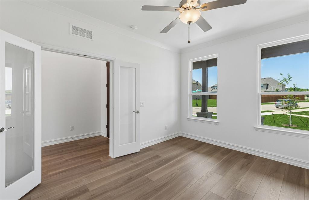 11220 Abbotsbury Road Fort Worth, TX 76052 - Photo 12 of 32 an empty room with wooden floor chandelier fan and windows