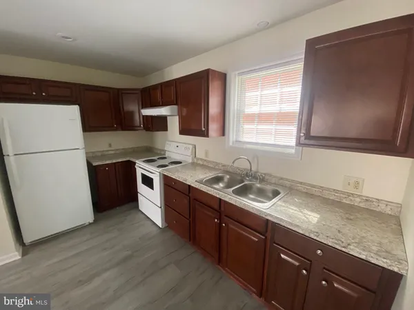 a kitchen with granite countertop a refrigerator a sink a stove a microwave and wooden cabinets