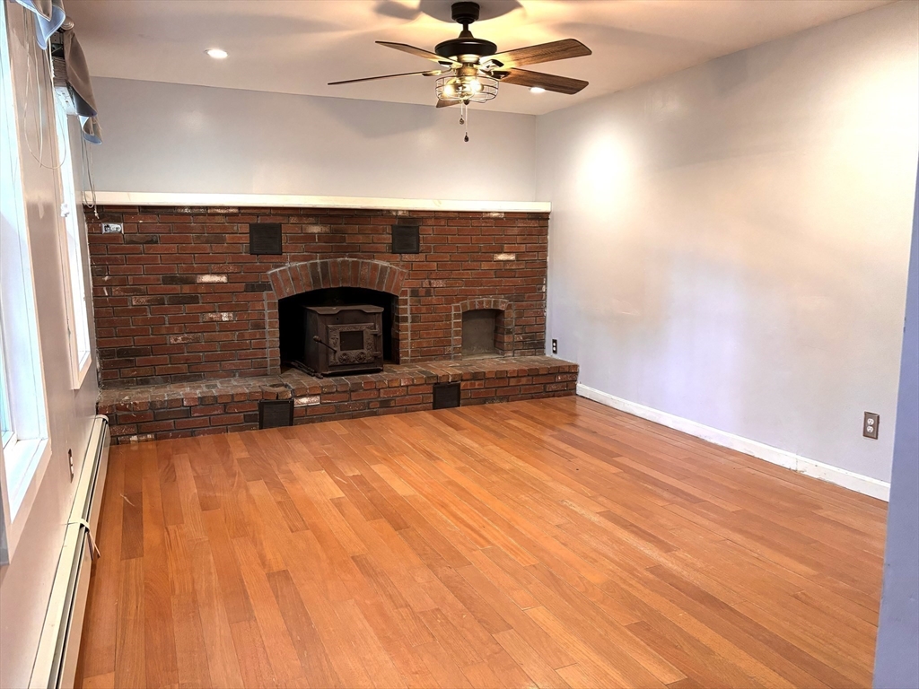 1694 Round Top Road Burrillville, RI 02830 - Photo 7 of 28 a view of a livingroom with a fireplace and a ceiling fan
