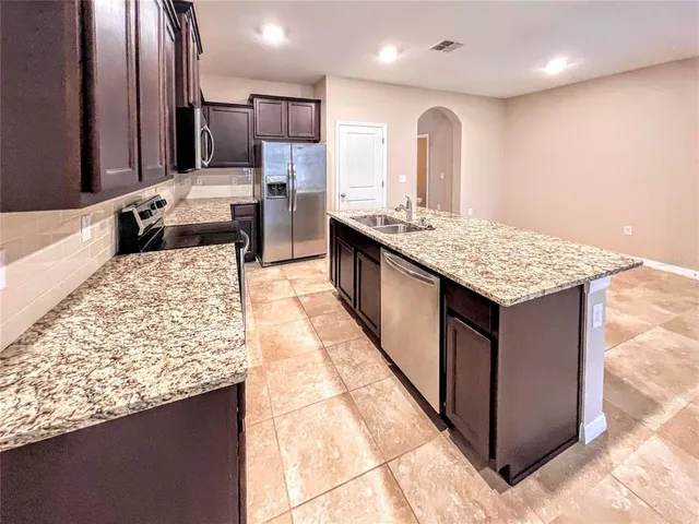 a large kitchen with kitchen island granite countertop a large counter top and wooden cabinets