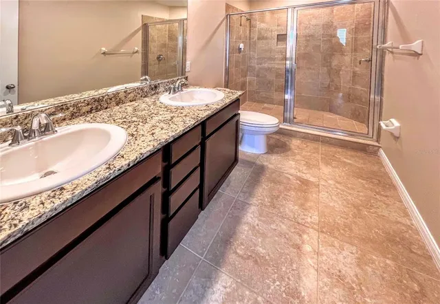 a bathroom with a granite countertop sink a toilet and shower