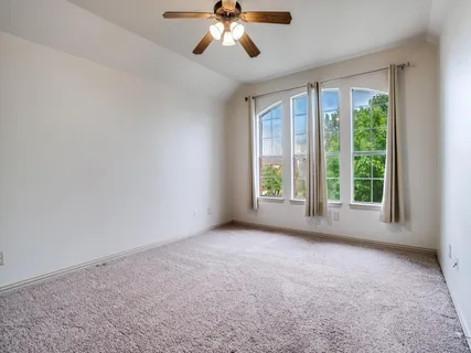 a view of a big room with windows and chandelier fan