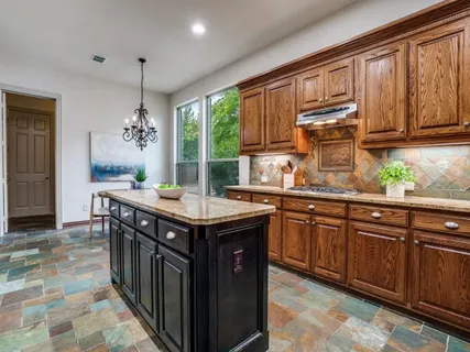 a kitchen with stainless steel appliances granite countertop a sink a stove and a wooden cabinets