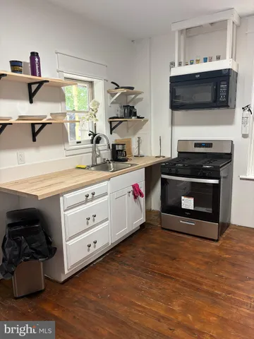 a kitchen with stainless steel appliances a stove and a wooden floor