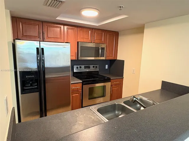 a kitchen with stainless steel appliances granite countertop a refrigerator a stove and a sink