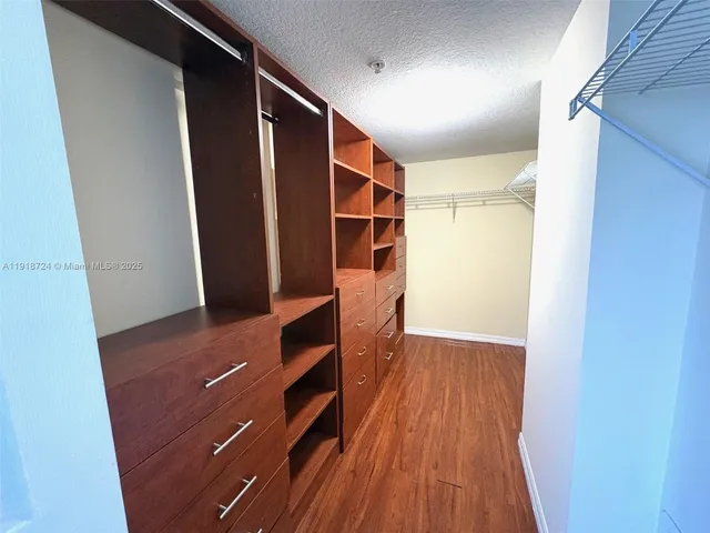 a view of walk in closet with wooden floor