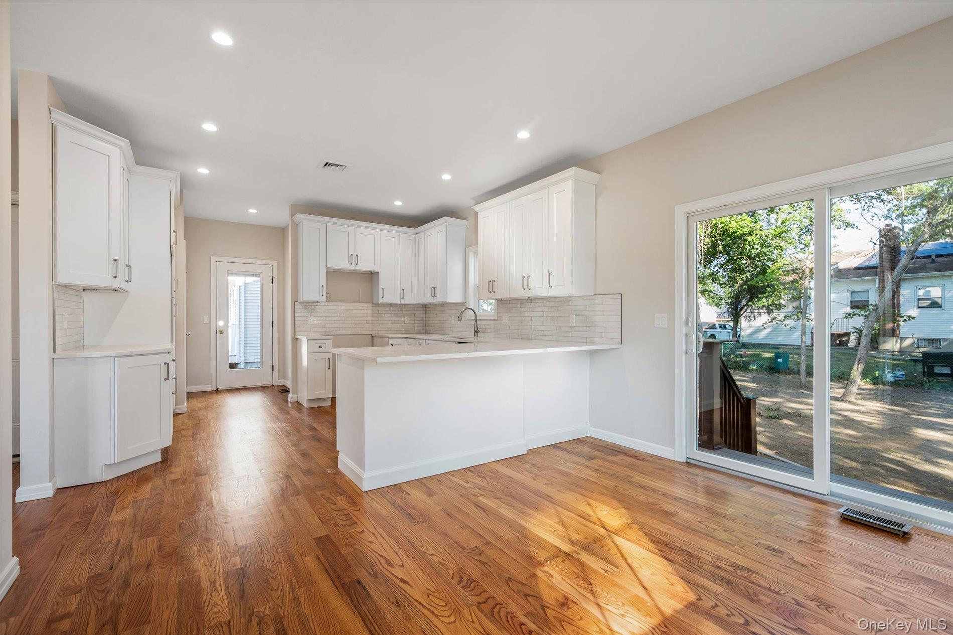 2 Gail-grace Court Copiague, NY 11726 - Photo 10 of 27 Kitchen featuring a peninsula, white cabinetry, light wood-type flooring, tasteful backsplash, and recessed lighting