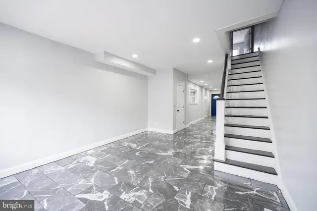 a view of an empty room with wooden floor and stairs