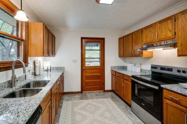 a kitchen with granite countertop a sink dishwasher stove and cabinets