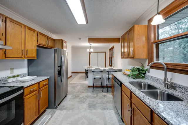 a kitchen with stainless steel appliances granite countertop sink stove refrigerator and cabinets