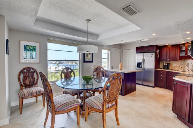 a kitchen with stainless steel appliances kitchen island granite countertop a table chairs in it and wooden floors