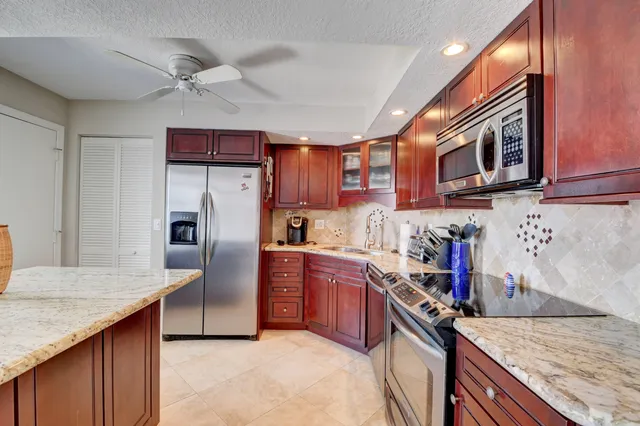 a kitchen with stainless steel appliances granite countertop a sink refrigerator and cabinets