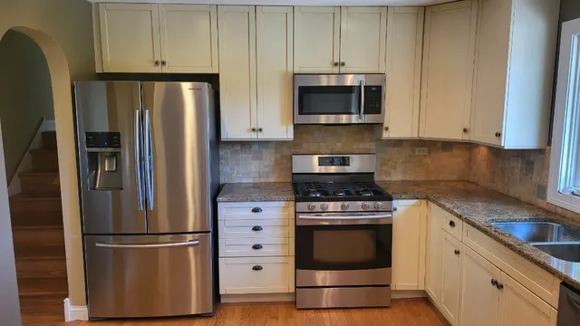 a kitchen with stainless steel appliances white cabinets and a stove a refrigerator with wooden floors