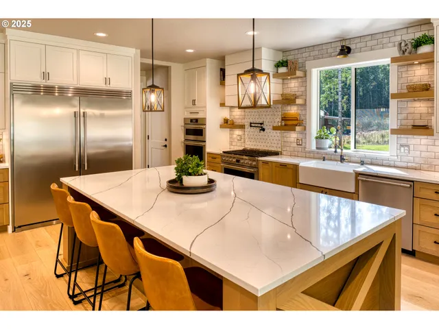 a kitchen with stainless steel appliances kitchen island granite countertop a table chairs and a refrigerator