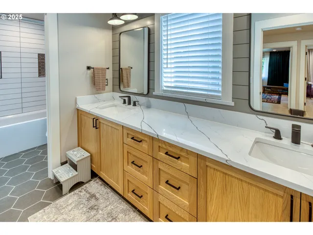 a bathroom with a sink double vanity granite tub and a mirror