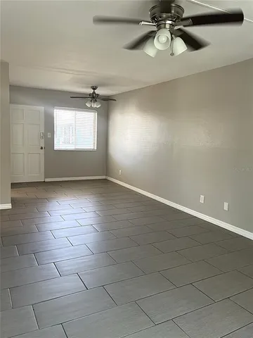 an empty room with windows and ceiling fan