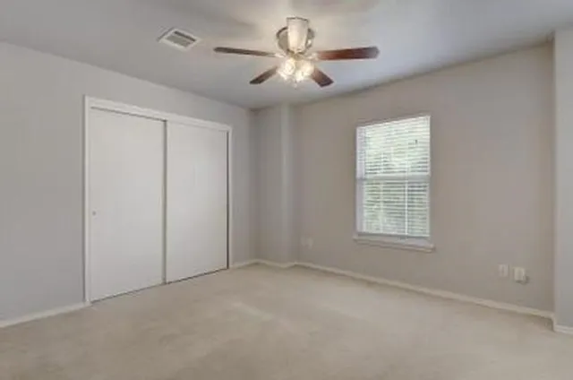 an empty room with windows and fan