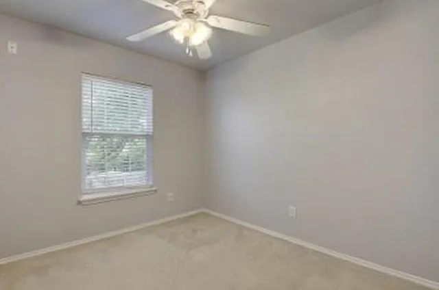 an empty room with a window and a fan