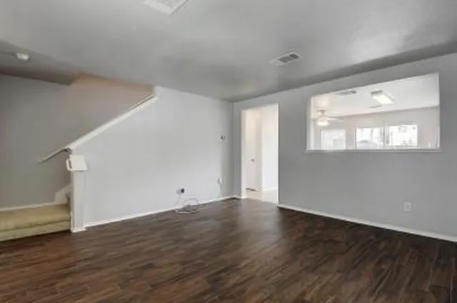 a view of an empty room with wooden floor and a window