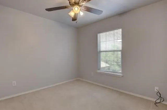 an empty room with a window and a fan