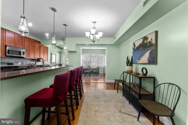 a kitchen with stainless steel appliances kitchen island granite countertop a stove a refrigerator a kitchen island a dining table and chairs with wooden floor