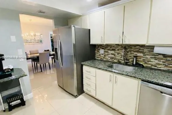a kitchen with granite countertop a refrigerator and a sink