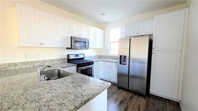 a kitchen with granite countertop a refrigerator and a stove top oven