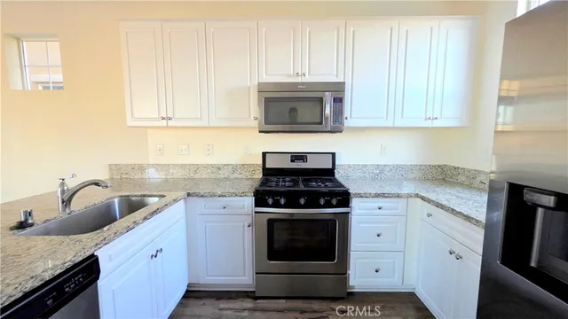 a kitchen with granite countertop white cabinets and stainless steel appliances