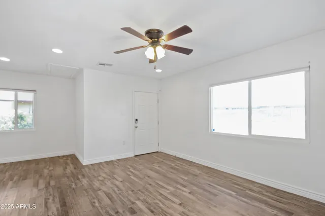 a view of empty room with wooden floor and fan