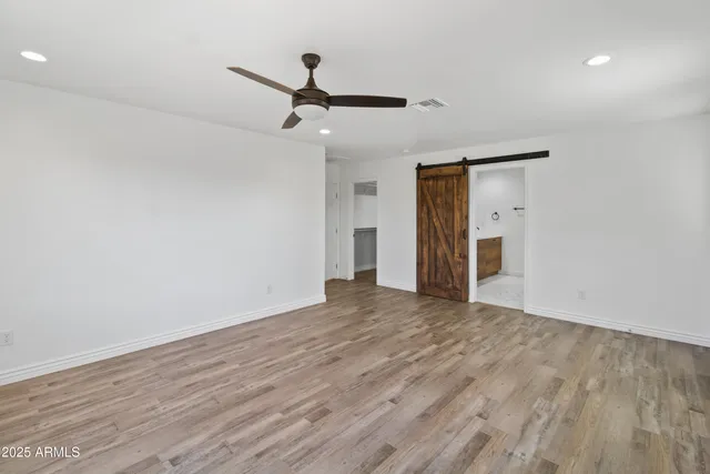 a view of empty room with wooden floor and ceiling fan