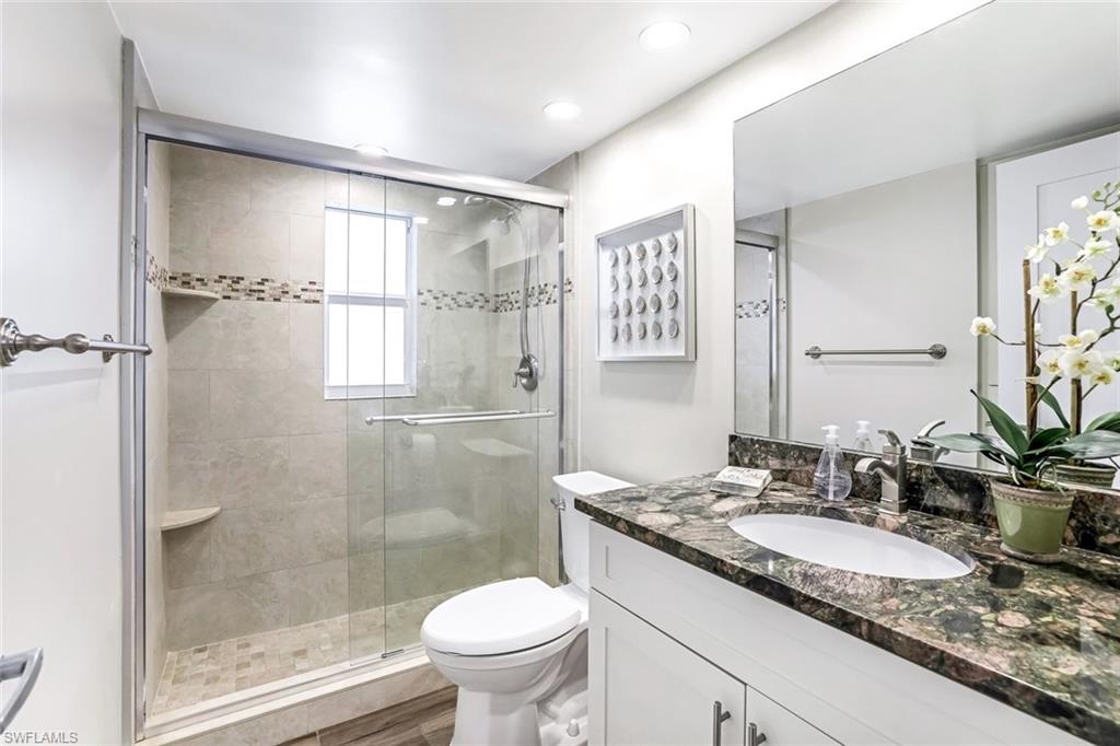 1100 8th Avenue South, Unit H227 Naples, FL 34102 - Photo 15 of 22 a bathroom with a granite countertop sink toilet and shower