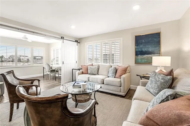 a living room with furniture a large window and wooden floor
