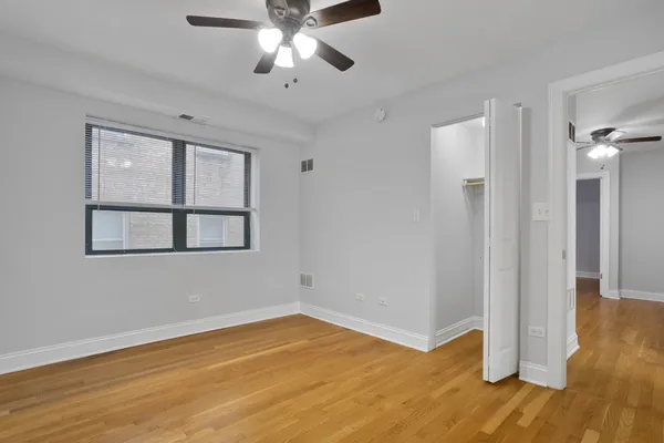 a view of empty room with wooden floor and fan