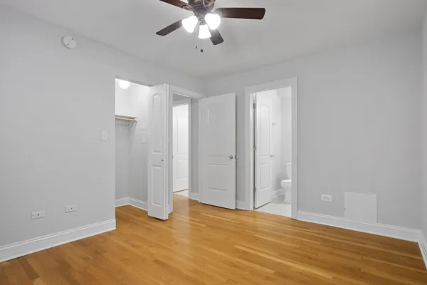 wooden floor in an empty room with a chandelier fan