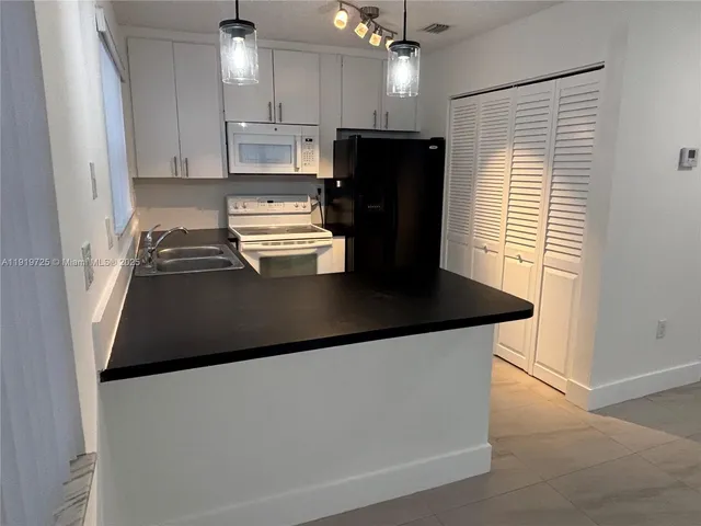 a kitchen with kitchen island a refrigerator a stove a microwave and island with wooden floor