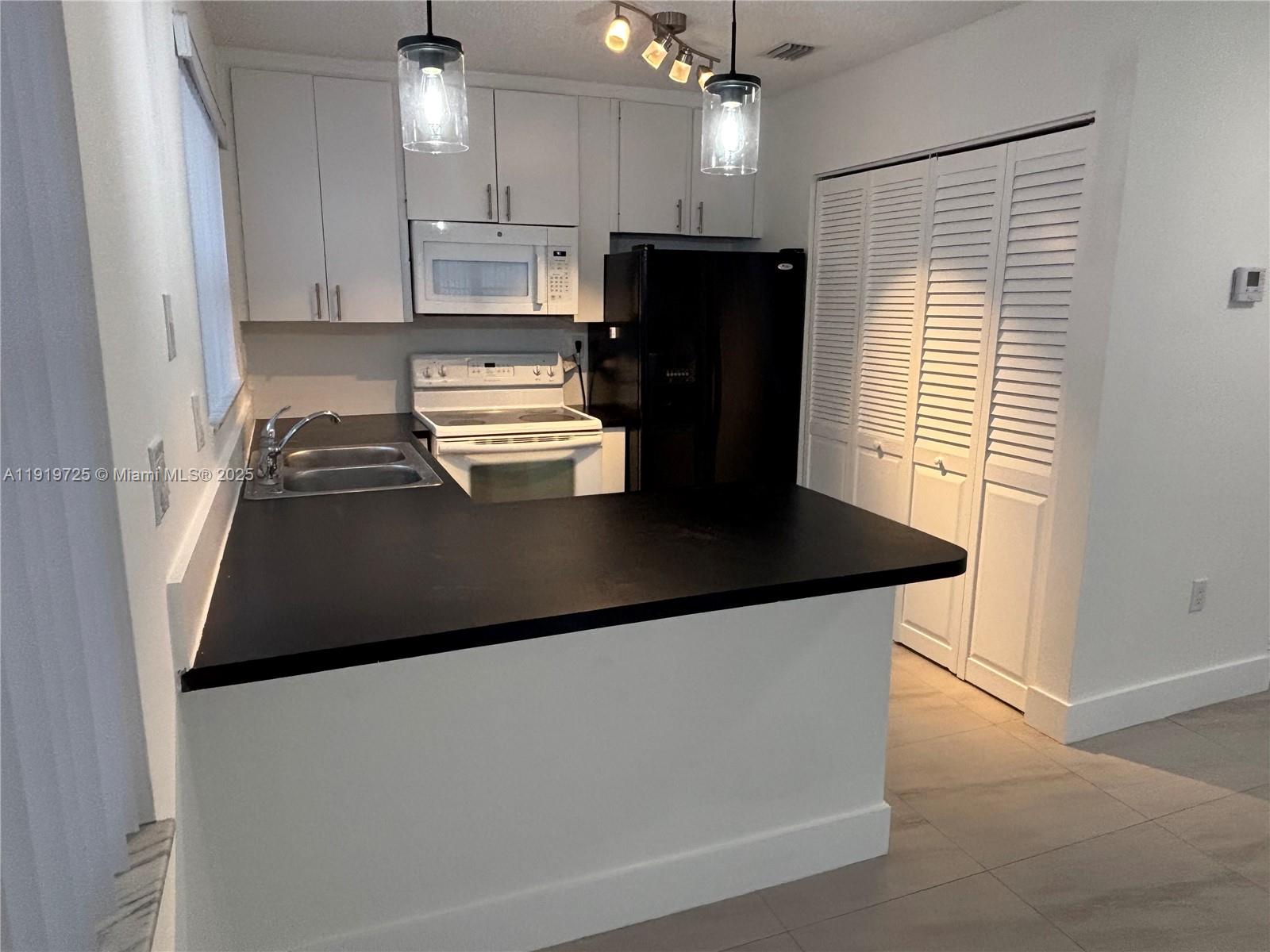 3616 Southwest 17th Street, Unit 3616 Miami, FL 33145 - Photo 13 of 16 a kitchen with kitchen island a refrigerator a stove a microwave and island with wooden floor
