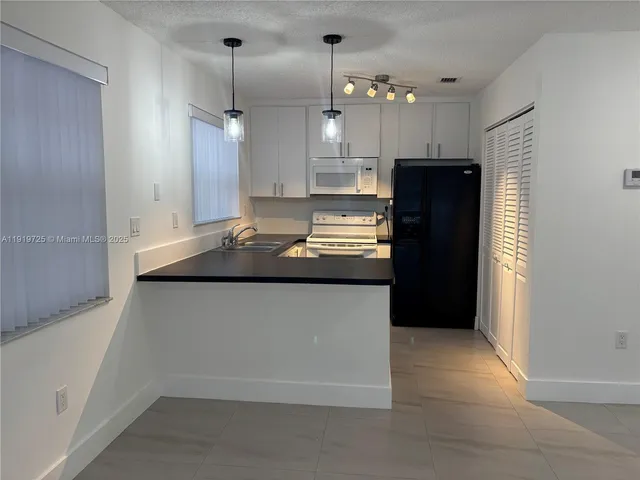 a kitchen with kitchen island a counter top space a refrigerator and a sink