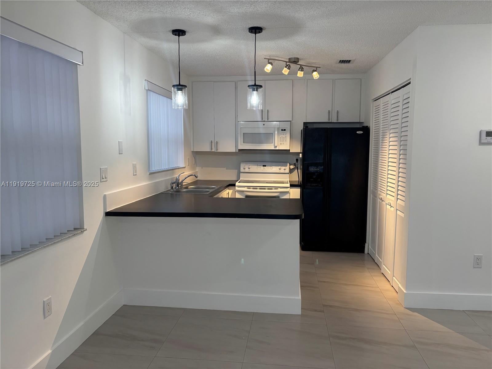 3616 Southwest 17th Street, Unit 3616 Miami, FL 33145 - Photo 14 of 16 a kitchen with kitchen island a counter top space a refrigerator and a sink