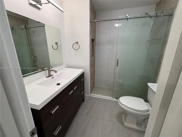 a bathroom with a sink a toilet a mirror and shower