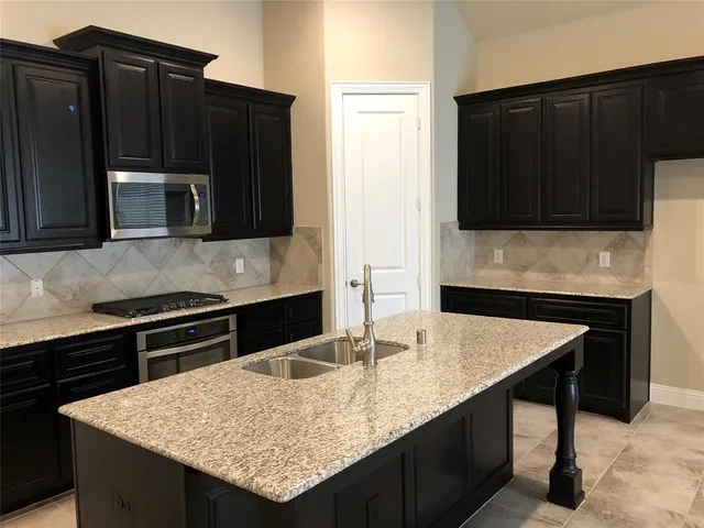 a kitchen with granite countertop a stove and a microwave with cabinets