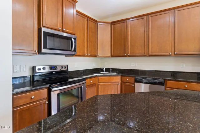 a kitchen with stainless steel appliances granite countertop a refrigerator a sink and a stove