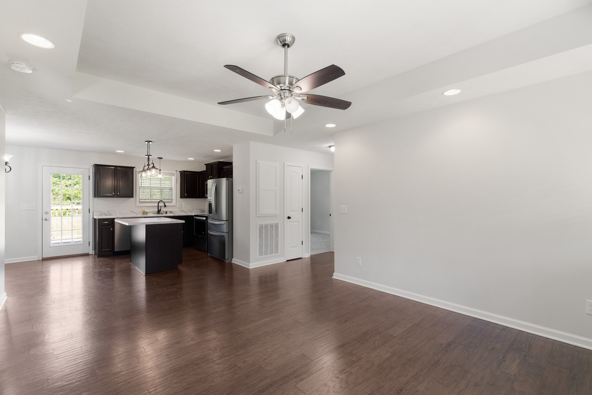 1821 Rock Bridge Road Bethpage, TN 37022 - Photo 5 of 31 a view of an empty room and kitchen with sink wooden floor and a ceiling fan