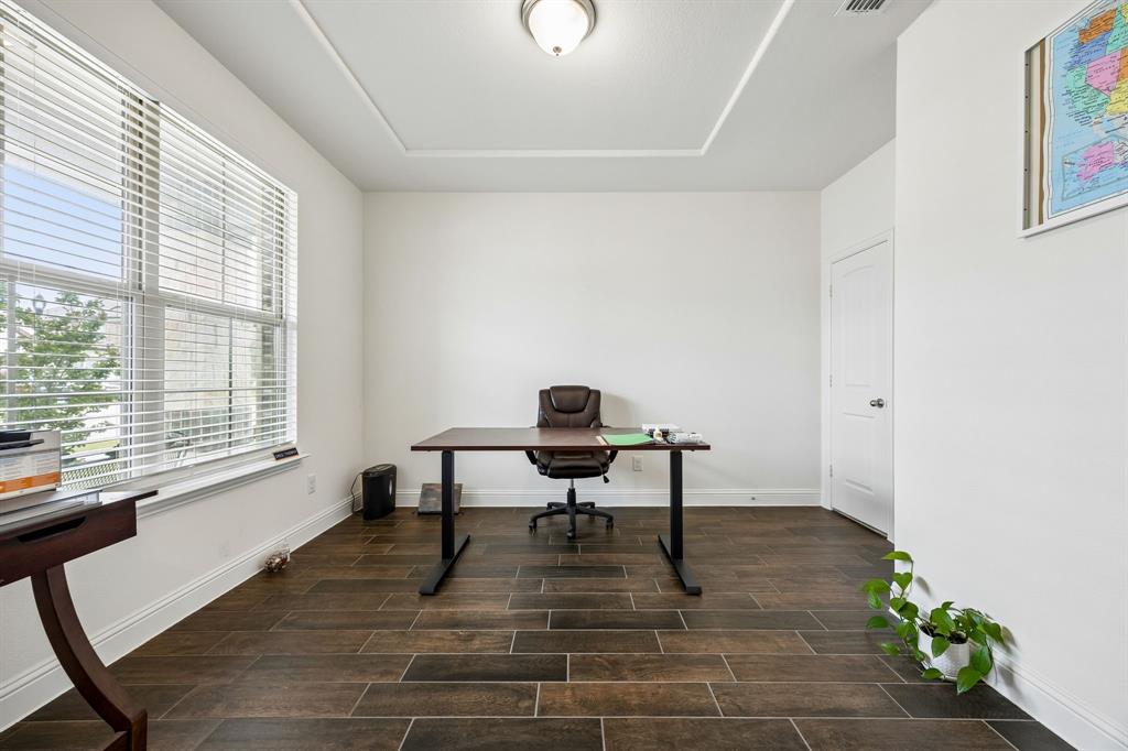 11732 Wulstone Road Fort Worth, TX 76052 - Photo 16 of 34 Spacious room featuring wood-finish tile flooring, a large window with blinds, a tray ceiling with a flush-mount light fixture, and a white paneled door