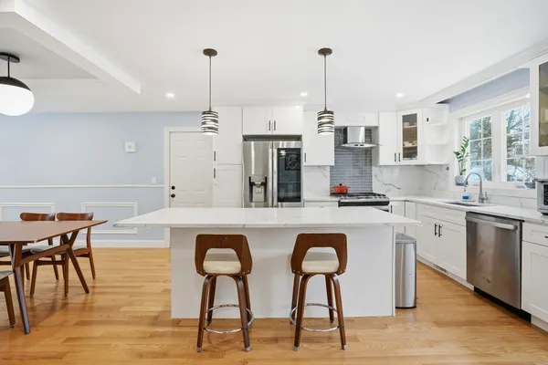 a kitchen with stainless steel appliances granite countertop a sink a stove a refrigerator and island with wooden floor